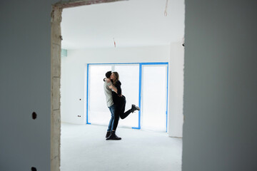 Fototapeta premium Happy young family just married couple in new building home house celebrating dancing getting mortrage loan house husband and wife in debt. Investing in new apartments. Good investment.