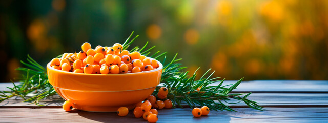 Sea buckthorn in a bowl against the backdrop of the garden. Selective focus. - obrazy, fototapety, plakaty