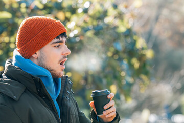 young man wrapped up in winter breathing halo of cold