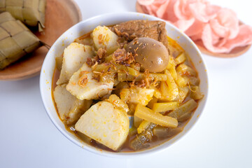 Ketupat Sayur or Lontong Sayur, a typical Indonesian food. Served with pumpkin vegetables, boiled eggs and tofu stew and crackers. Served during Ramadan, Eid al-Fitr and Adha. White Background