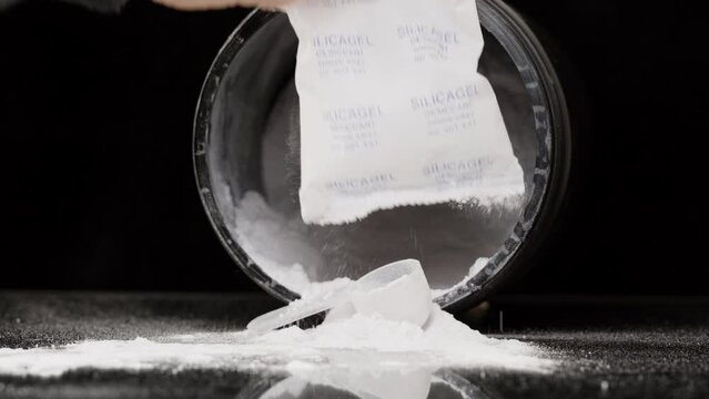 A Man Takes Out a Packet with Silica Gel from a Jar with White Powder, Creatine, or Another Supplement with a Measuring Spoon Inside.