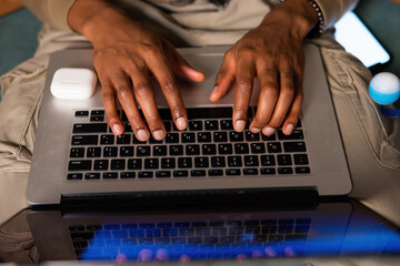 Close up shot selective focus african man's hands sending email or messages to colleagues clients...