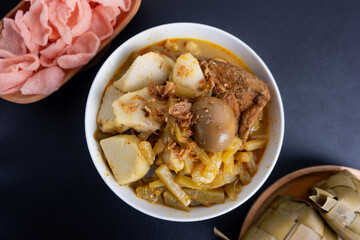 Ketupat Sayur or Lontong Sayur, a typical Indonesian food. Served with pumpkin vegetables, boiled eggs and tofu stew and crackers. Served during Ramadan, Eid al-Fitr and Adha. Black Background
