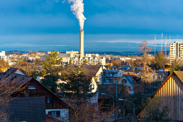 Scenic view of skyline of Swiss City of Zürich on a cloudy sunny winter morning with smoking...