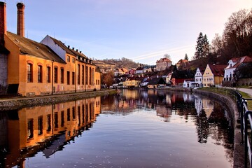 A view to the calm surface of Vltava river with water reflection of historical city Cesky Krumlov,...