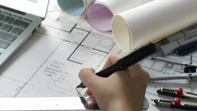 Female Architect working with blueprints for architectural plan, sketching a construction project concept. view of female hands architect drawing building plan with pencil concentrated on blueprint.