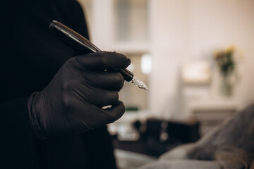 tattoo machine in female hands in black gloves.tattoo permanent makeup beauty workshop