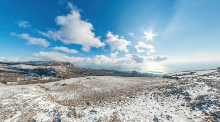 Winter snow mountain panorama. panoramic aerial view above sea and snow covered frozen mountains with deep blue sky and a beautiful radiant sun. Cold weather and climate change