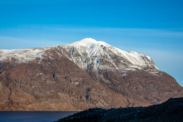 Liathach mountain in Torridon in winter with snow and natural water reflection in the loch