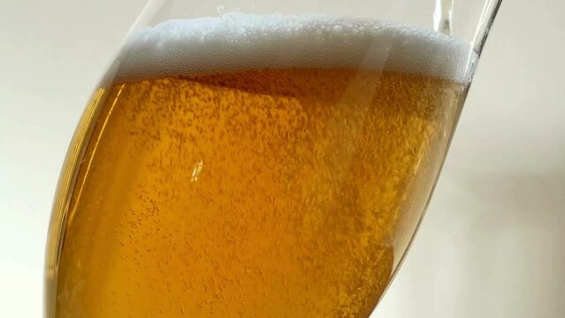 Pouring beer into glass. Closeup slow motion shot. Bubbles rising up stream of a