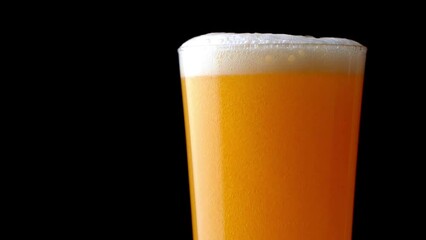 Light beer is poured in a glass. Closeup. Slow motion lager, IPA, and other