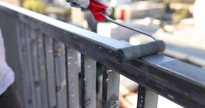 Work process paints steel pipe gray with roller on terrace