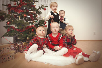 Children at time of christmas day posing together near tree