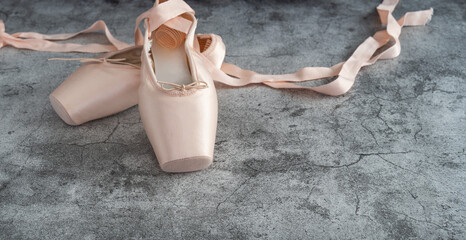 conceptual dichotomy of warm, soft and elegant dance shoes on a cold and hard gray stone floor