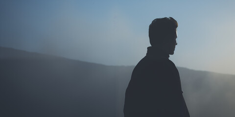 Silhouette of a contemplative man against a foggy landscape, merging with the misty horizon