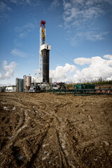 Fototapeta na wymiar Rig in an oil field with dirt and mud in the foreground, set against a stunning blue sky