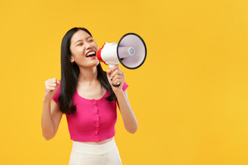 Photo of a young Asian woman holding a megaphone surprised with a happy face, wearing a pink...