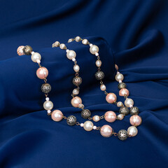 Mother-of-pearl beads are lying on the blue drapery