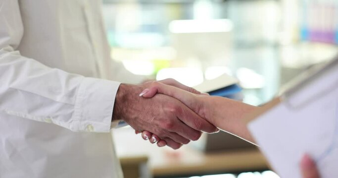 Businessman shaking woman hand and holding documents
