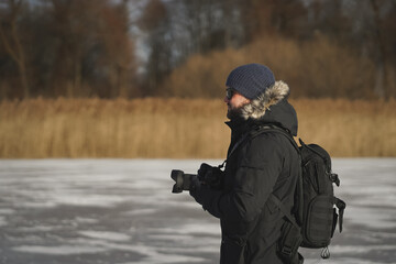 Fototapeta premium Male landscape photographer outdoors with a camera in his hands, side view.