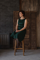 an adult woman sits thoughtfully on a chair, sofa. woman dreams, sits in dark interior