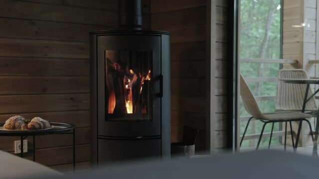 Cozy house chimney fire place in black color with fire burning in, tiny house, cabin house interior, wooden wall, backgrounds, slow motion.