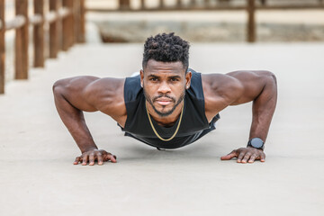 Fototapeta premium Motivated black sportsman doing push ups in park