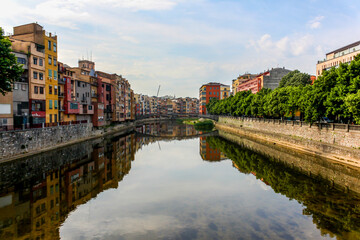 Fototapeta na wymiar View of the Onyar River in Girona, Spain with the reflection of the buildings and bridge. 