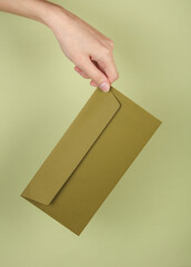 Hand holding envelope on green background