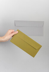 Hand holding envelopes on gray background