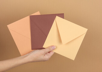 Hand holding envelopes on beige background