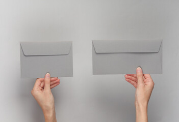 Hands holding envelopes on gray background