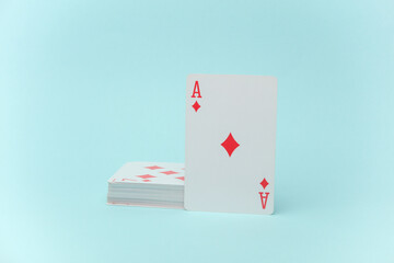 Ace of diamonds and stack of playing cards on blue background