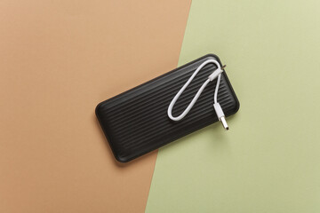 Black power bank with cable on green beige background