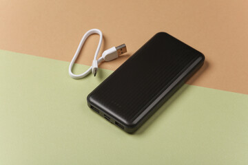 Black power bank with cable on green beige background