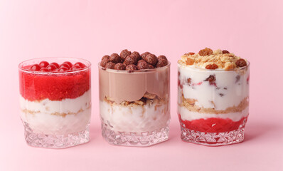 Homemade layered Desserts in a glass cups with yogurt, berries and chocolate on a pink background
