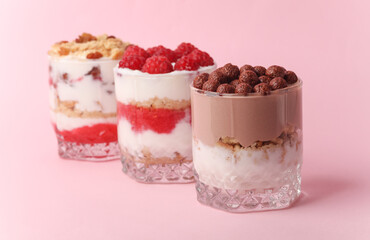 Homemade layered Desserts in a glass cups with yogurt, berries and chocolate on a pink background