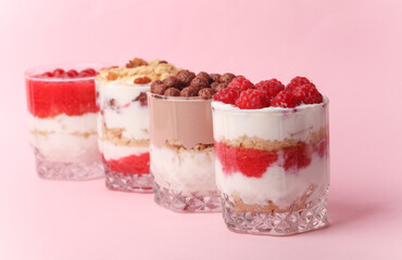 Homemade layered Desserts in a glass cups with yogurt, berries and chocolate on a pink background