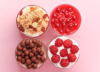 Homemade layered Desserts in a glass cups with yogurt, berries, cookie and chocolate on a pink background