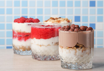 Homemade layered Desserts in a glass cups with yogurt and chocolate balls on table