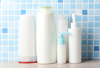 Many different shampoo and other cosmetic product bottles on a tile background