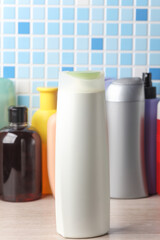 Many different shampoo and other cosmetic product bottles on a tile background