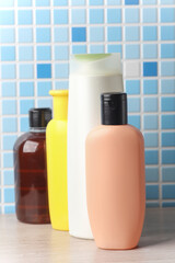 Many different shampoo and other cosmetic product bottles on a tile background