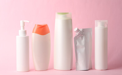 Many different shampoo and other cosmetic product bottles on pink background