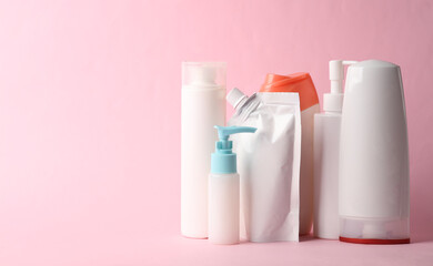 Many different shampoo and other cosmetic product bottles on pink background