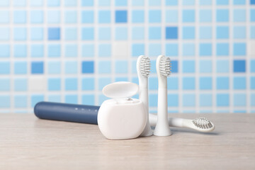 Modern smart ultrasonic toothbrush with heads and dental floss on the table