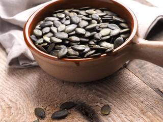 Tasty organic pumpkin seeds in a ceramic bowl on a wooden kitchen table