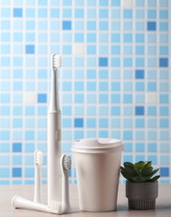Modern smart ultrasonic toothbrush with heads, coffee cup  on the table