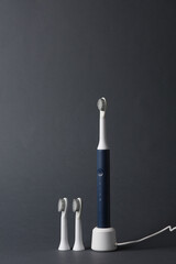 Modern smart ultrasonic toothbrush with heads on dark gray background