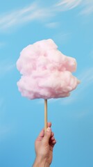 Handheld Delight: Whimsical Pink Cotton Candy Against a Serene Blue Sky. Generative AI